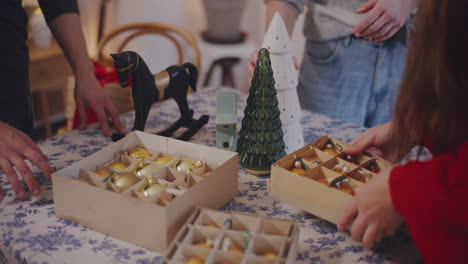 friends placing christmas ornaments on table