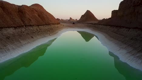 Aerial-move-forward-to-setup-tent-camping-close-to-the-green-lake-in-the-desert-in-Shahdad-Kerman-Iran-at-sunset-golden-time