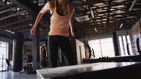 video of fit caucasian woman jumping on block at gym