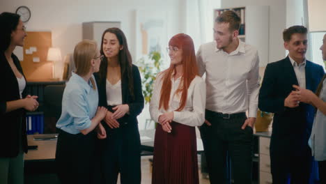 Happy-employees-discussing-while-standing-in-office.