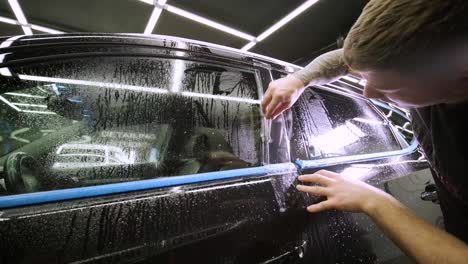 hombre que cubre el coche con cinta de poliuretano de vinilo. películas para el coche. pegatina película protectora en el coche