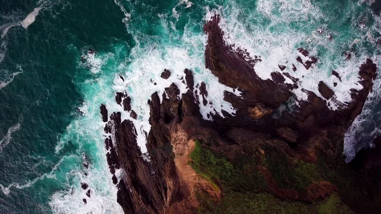 Onde dell'oceano si infrangono su una punta rocciosa a Big Sur, California, ampia ripresa aerea con drone