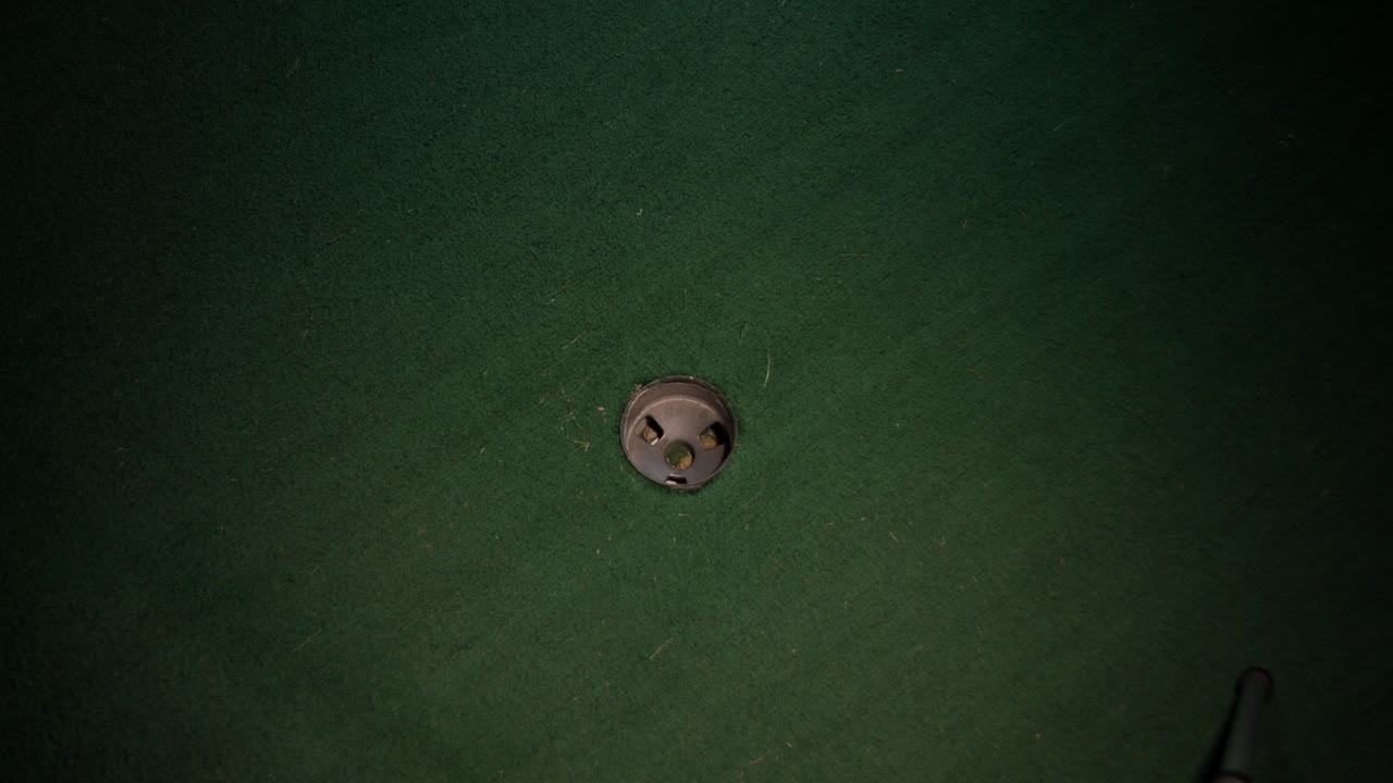 홀에 들어가는 노란색 미니 골프공의 넓은 샷