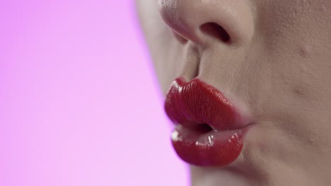 Primer-Plano-De-Los-Labios-De-Una-Mujer-Sexy-Con-Lápiz-Labial-Rojo-Que-Sopla-Un-Beso-Con-La-Mano-De-Esmalte-De-Uñas-Rosa,-Foto-De-Estudio