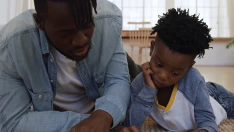 father and son reading a book together at home