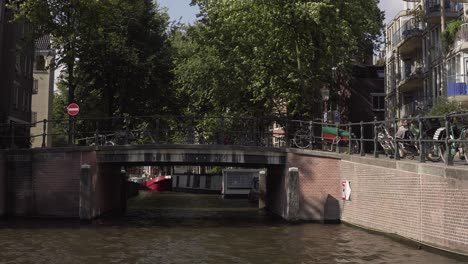 Navigieren-Sie-Mit-Einem-Touristischen-Boot-Durch-Die-Kleinen-Kanäle-Der-Stadt-Amsterdam