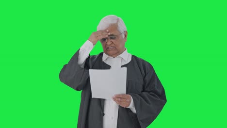 Tensed-and-stressed-Indian-senior-lawyer-reading-court-case-papers-Green-screen