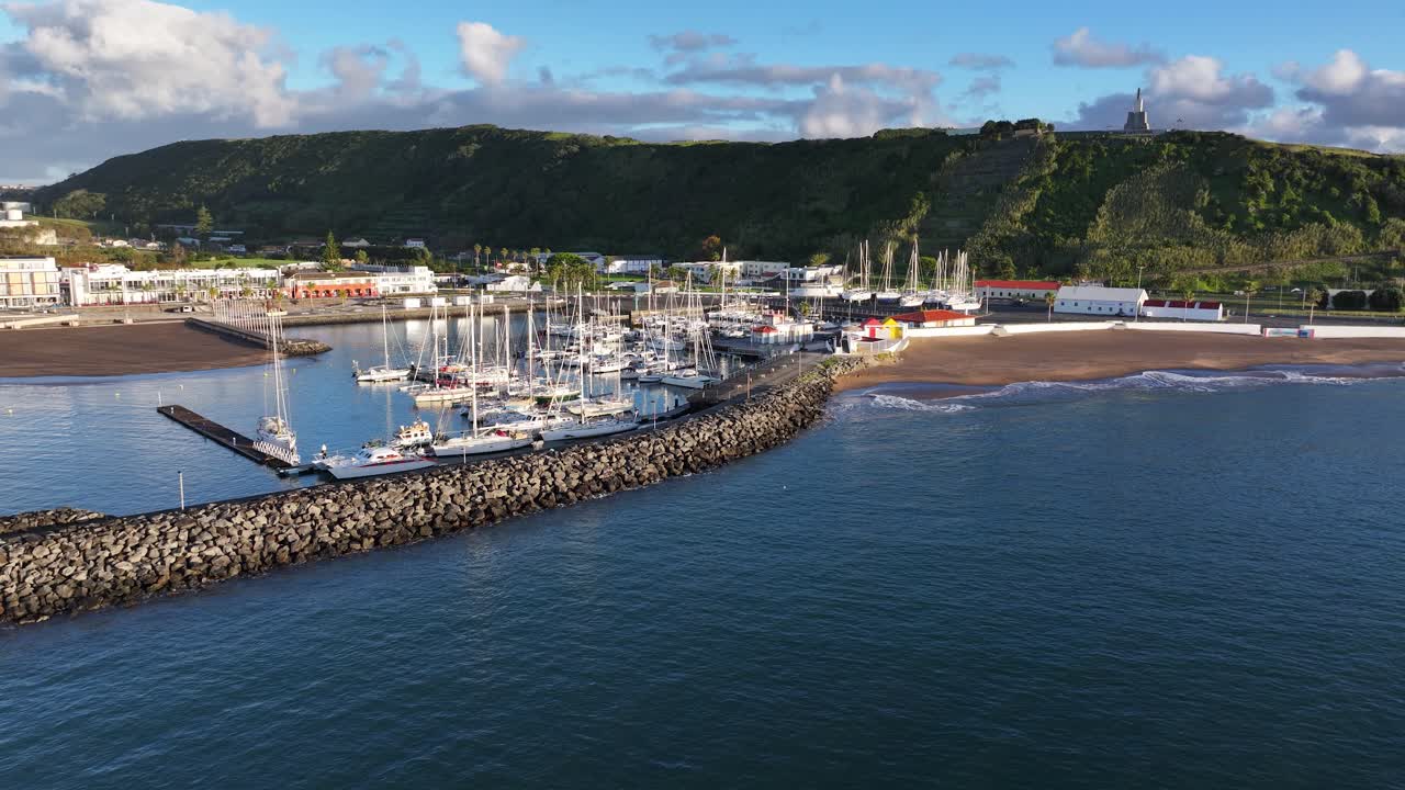 Breakwater at Praia da Vitória marina and waves lapping onto small beach, aerial