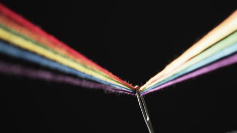 video de micro de hilos de color arco iris que pasan a través de la aguja con espacio de copia en fondo negro