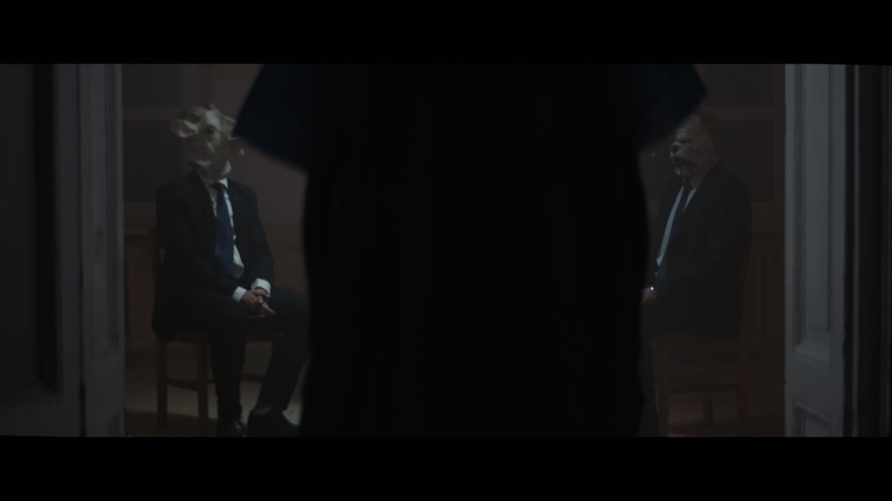 A girl sits at a table with strange figures in animal masks