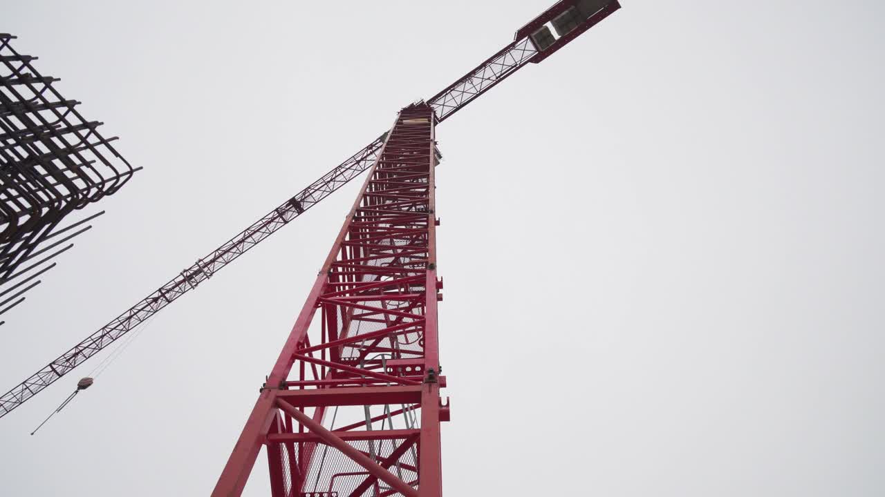 Red crane and reinforced concrete rods, low angle rotating view