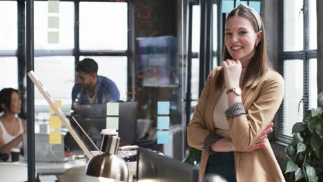 Young-Caucasian-woman-in-business-attire-stands-confidently-in-business-office-with-copy-space