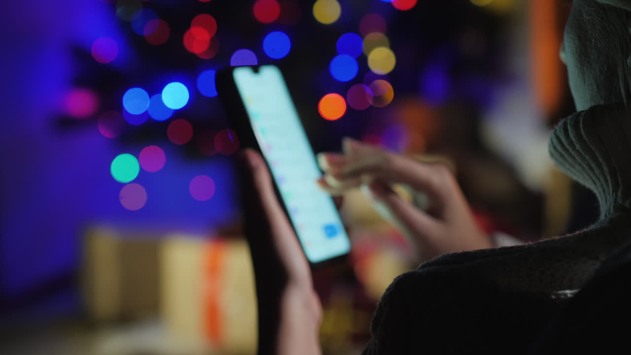 emale manos con un teléfono inteligente sobre un fondo de luces de árbol de navidad concepto de orden de regalo