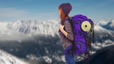 woman with backpack standing against winter landscape with snowy mountain ranges