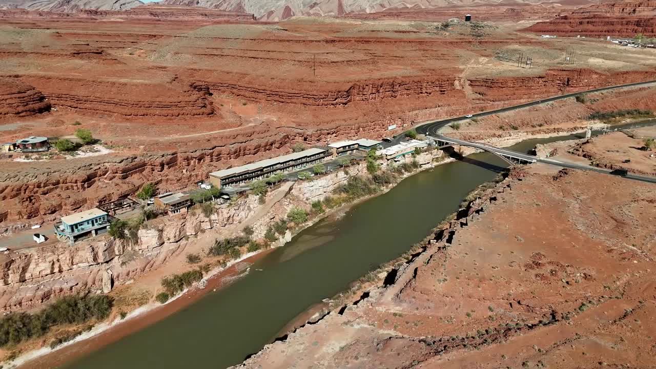 Aerial View of Mexican Hat Utah, Hotels and parking lot with views of San Juan River and Jason R. Workman Memorial Bridge, push in shot, Brush and Vibrant Orange Cliffs, Highway 163