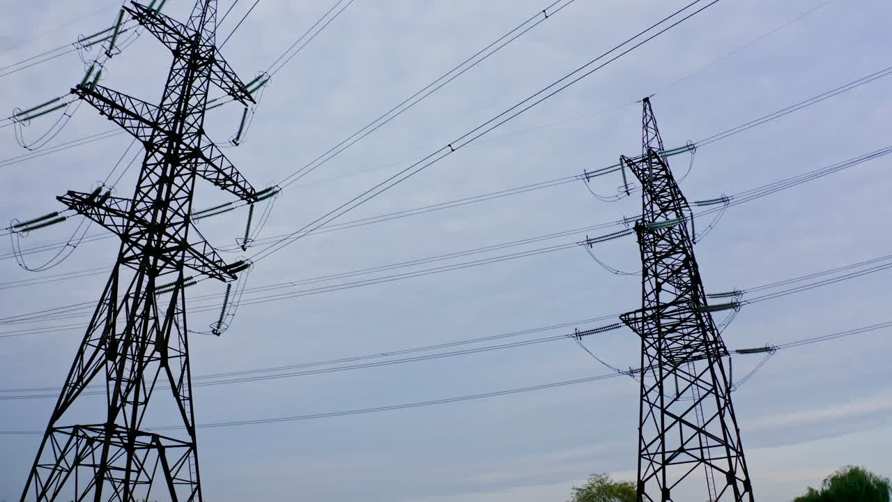 Transmission lines in nature. High voltage electric towers on blue sky background. Tall steel pylons and wires distribute electricity.