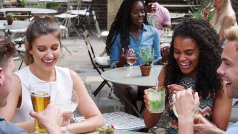 group of friends meeting for drinks at outdoor tables in restaurant