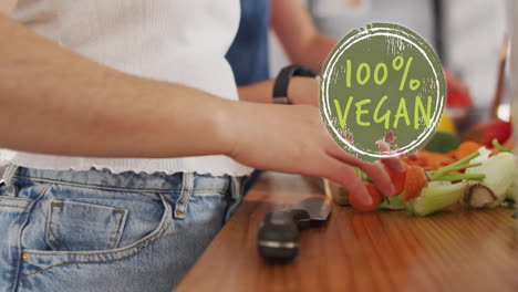 animación de texto 100 por ciento vegano sobre una pareja de mujeres diversas cocinando en casa