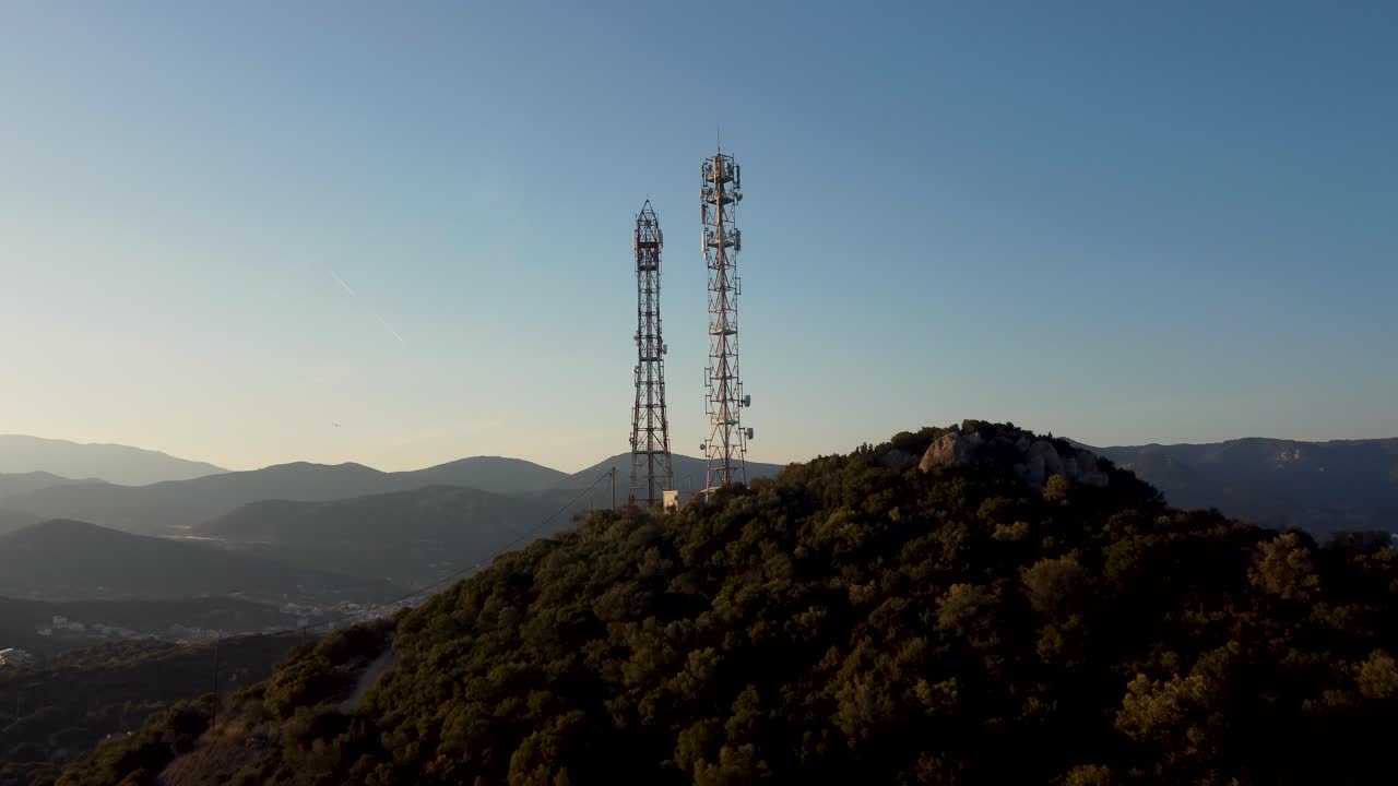 Aerial approaching antennas, telecommunications towers at sunset