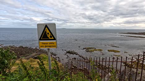 warning sign near cliffs by the sea