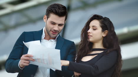 Closeup-business-partners-reading-documents.-Couple-discussing-project-outside