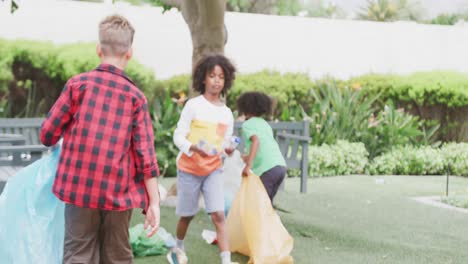 video de tres escolares diversos recogiendo basura para reciclar en el patio de la escuela, espacio de copia