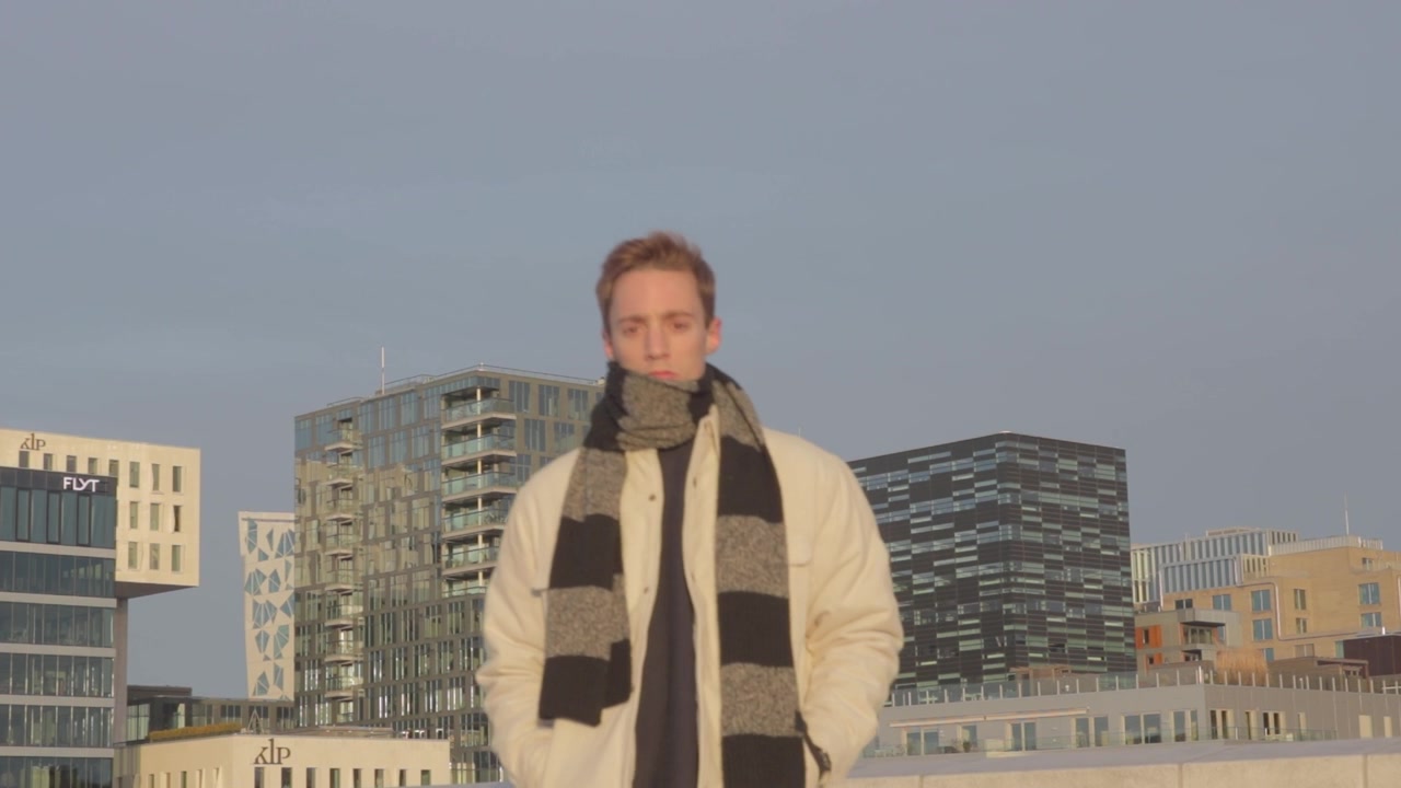 Confident Caucasian millennial in winter attire looking at the modern cityscape in Norway