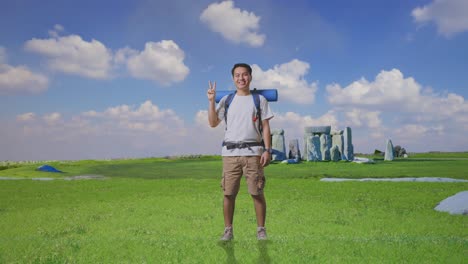 full body of asian male hiker with mountaineering backpack smiling and showing peace gesture while traveling in stonehenge