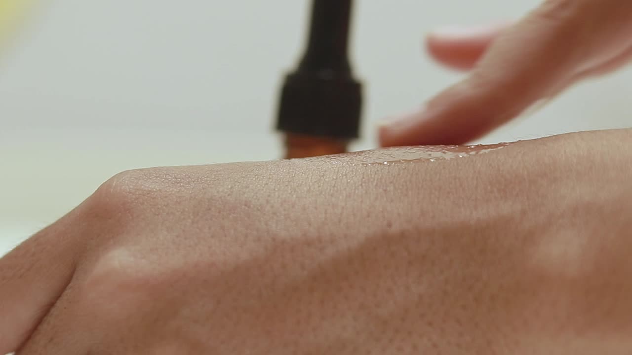 Close up to testing serum from a brown glass bottle with dropper on skin of a hand showing skincare and cosmetic