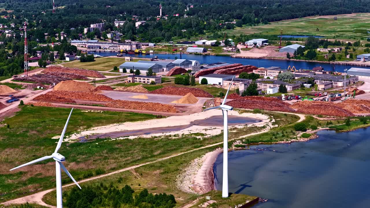 Wind turbines on coastal Latvian village, aerial cinematic shot of industrial site