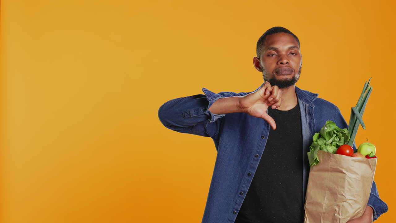 joven adulto mostrando un símbolo de pulgar hacia abajo en el estudio