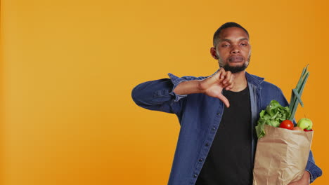 young adult showing a thumbs down symbol in studio