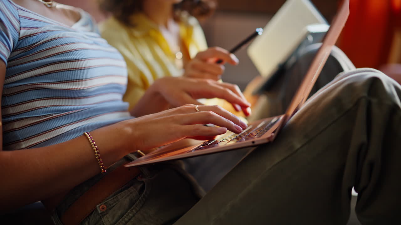 Two friends making homework at home closeup. Curly brunette holding copybook