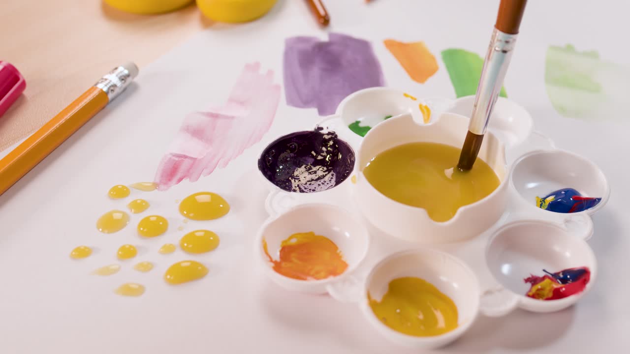 Bambino usa un pennello per mescolare e applicare colori su carta in un ambiente artistico luminoso e organizzato