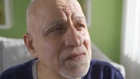 close-up depressieve oude gepensioneerde man die op de bank zit, zich eenzaam en ongelukkig voelt.