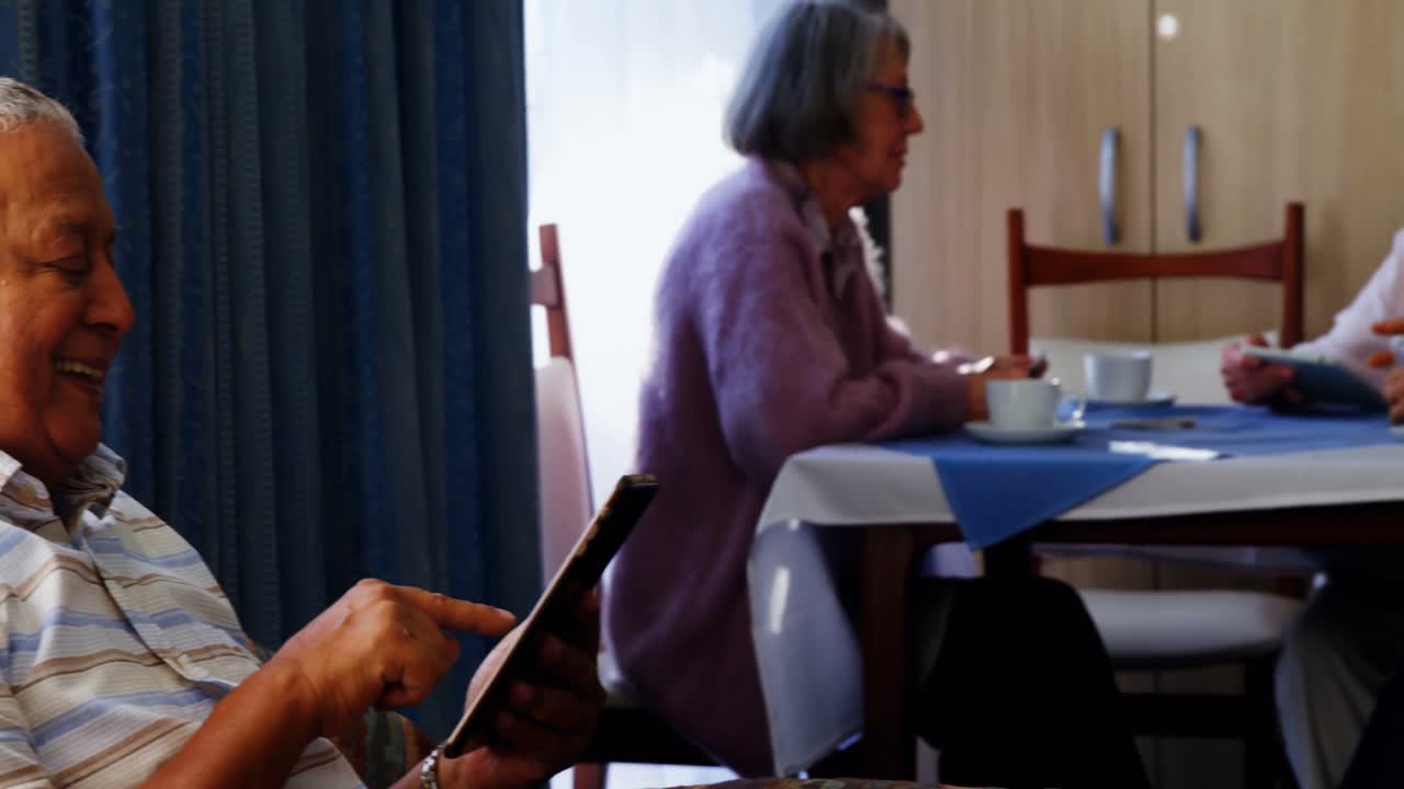 배경 4k에 앉아있는 그의 친구들과 함께 디지털 태블릿을 사용하는 노인