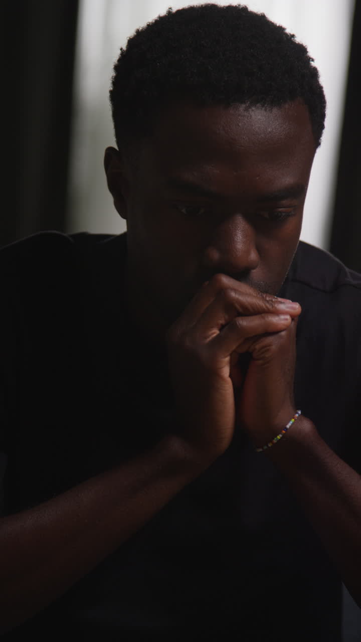 video vertical de un joven infeliz y deprimido sentado en el sofá en casa mirando ansioso y preocupado 1