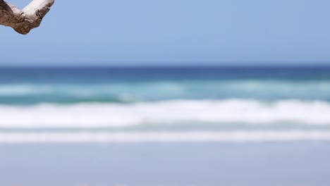 a serene view of ocean waves rolling onto a sandy shore under a clear blue sky.