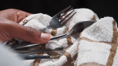mano sosteniendo platos de plata en una toalla