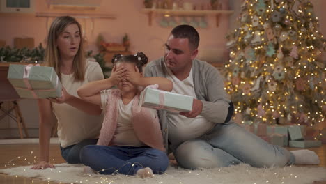 mother and father give christmas presents to surprised little girl