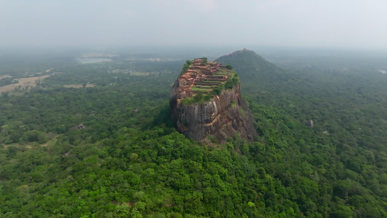 Dronefoto ovenfra av Sigiriya Rock Fortress-ruinene i Sri Lanka, som viser terrasser, murer og vannhage omgitt av jungel