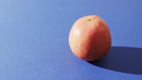 Video-of-close-up-of-orange-with-copy-space-over-blue-background