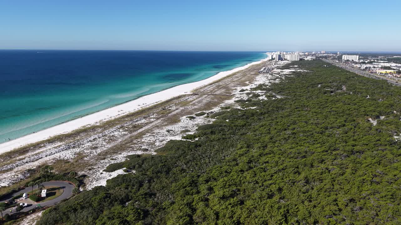 Amazing panoramic drone fly at long sandy coastline bordered by greenery field meeting blue ocean, 30A, Florida, USA