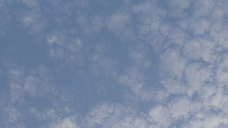 Large blue sky speckled and dotted with mushroom like clouds broken through sky, time lapse