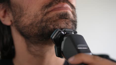hombre afeitando su barba y bigote con una afeitadora eléctrica, línea de la mejilla