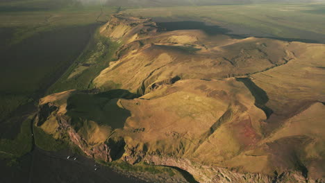 aerial reverse dolly over golden cliff on edge of black sand beach, iceland