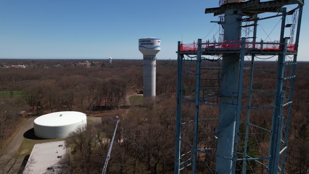 una vista aérea de una torre de agua siendo desmantelada en un día soleado en long island, nueva york