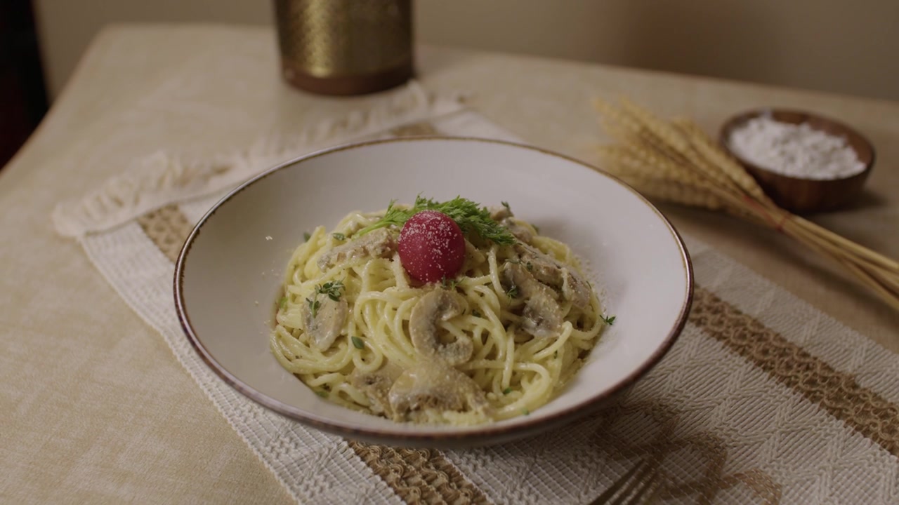 Spaghetti cremosi con funghi ed erbe aromatiche serviti in una ciotola su un tavolo da pranzo con arredamento rustico