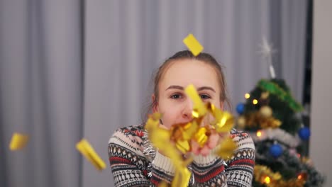 close up view of beautiful woman blowing gold glitter confetti at home in slow motion. beautiful young party woman blowing gold