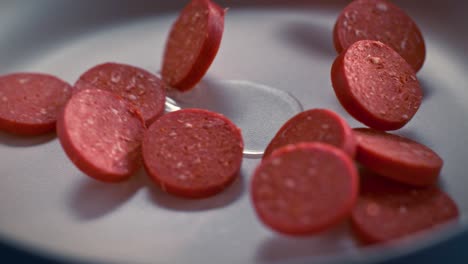 sliced turkish sausages (sucuk) fall into the pan in slow motion.